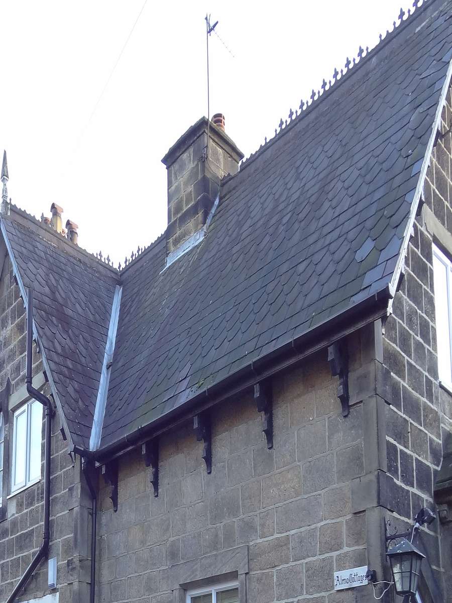 Stone cottage gable with a chimney stack above a slate roof