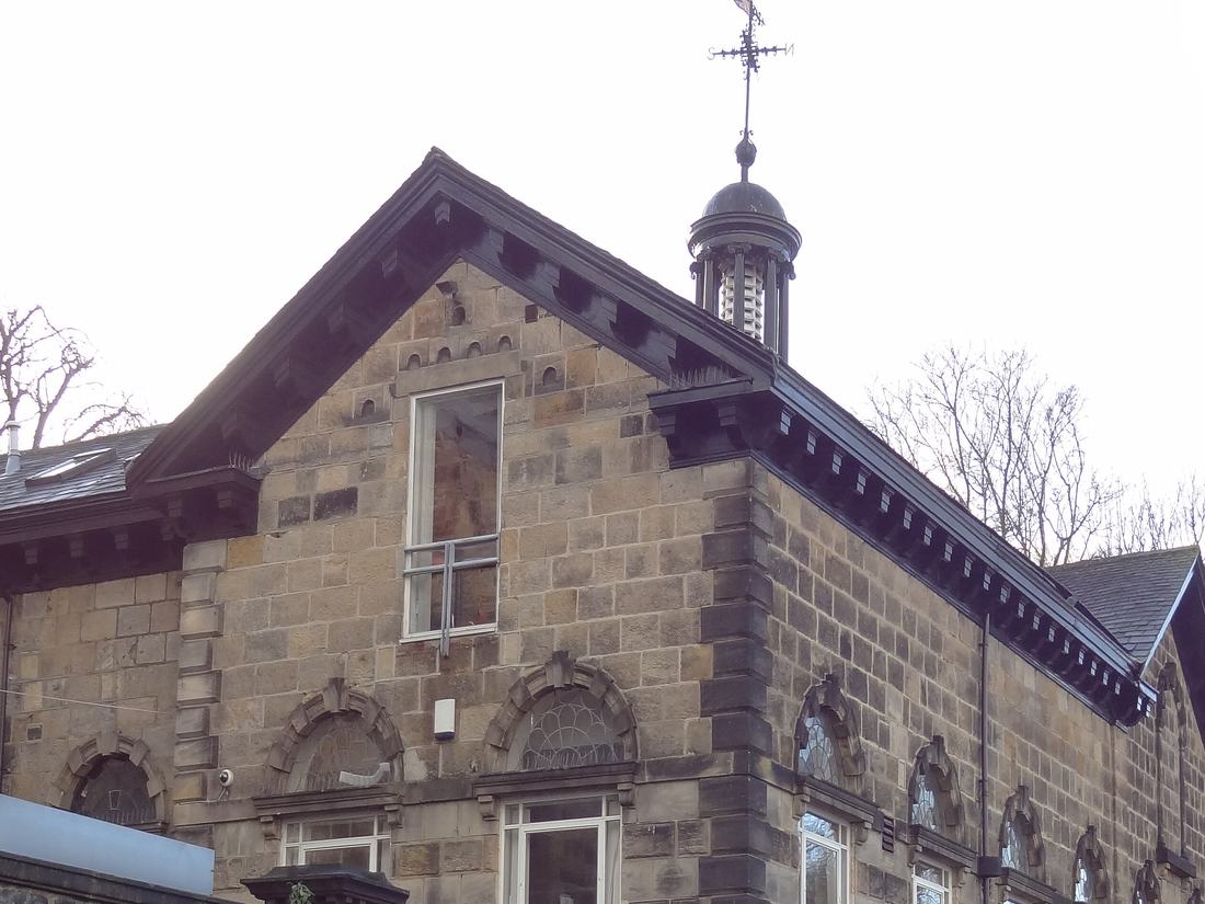 Stone gable with bracketed eaves under a slate roof