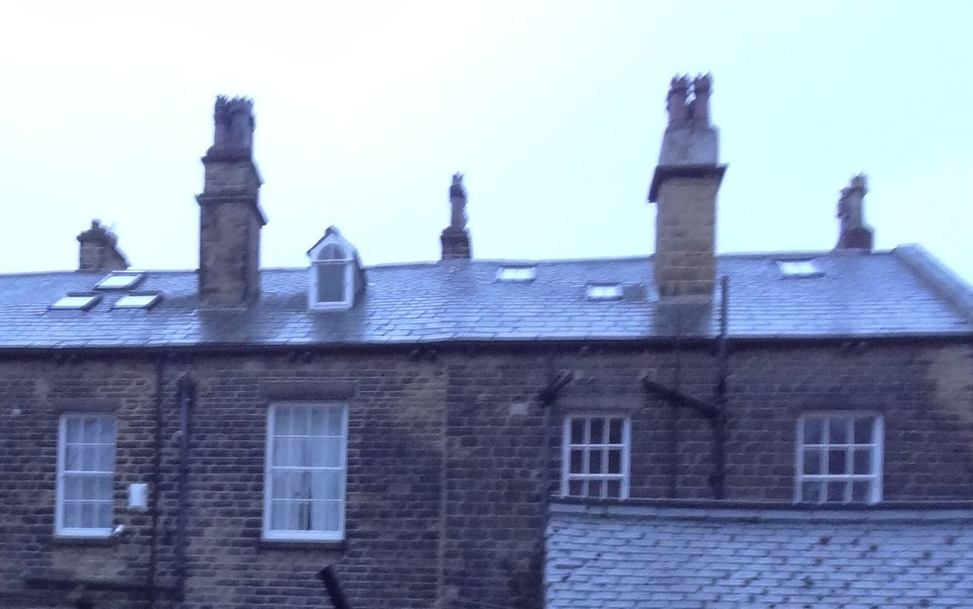 Row of stone chimney stacks and clay pots on a slate roof